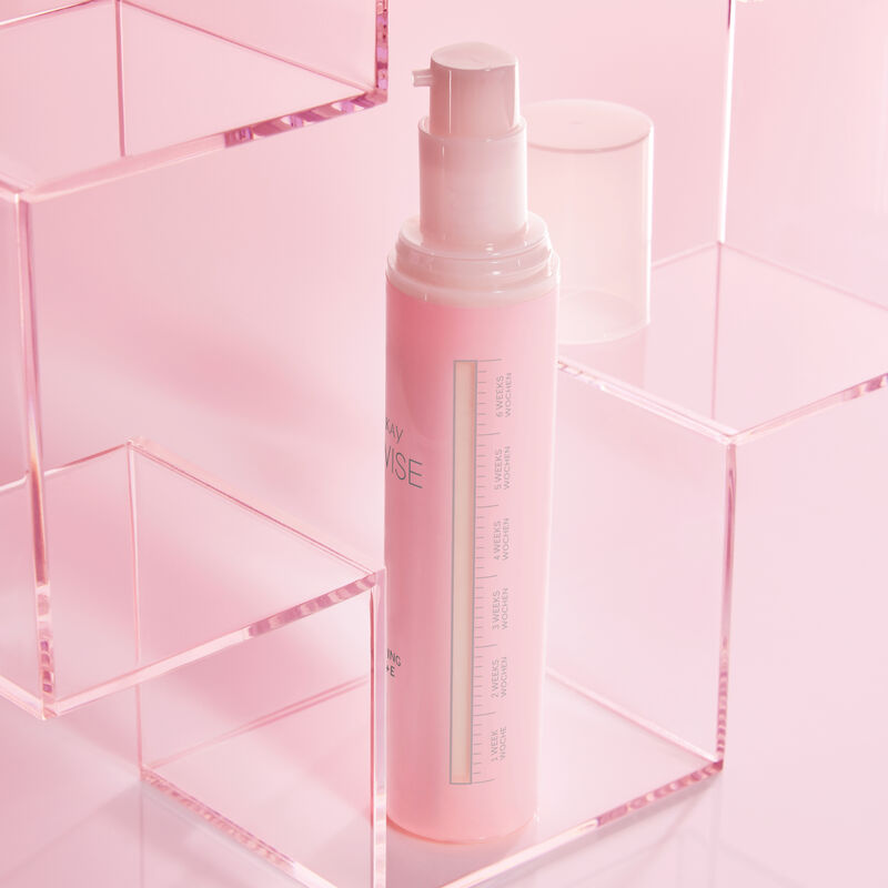 Side view of TimeWise Replenishing Serum C+E showing 6-week usage gauge standing in a clear acrylic shelf on pink background