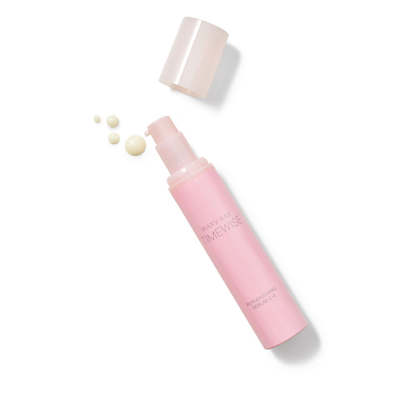 Uncapped bottle of TimeWise Replenishing Serum C+E and product dots laying down on plain background