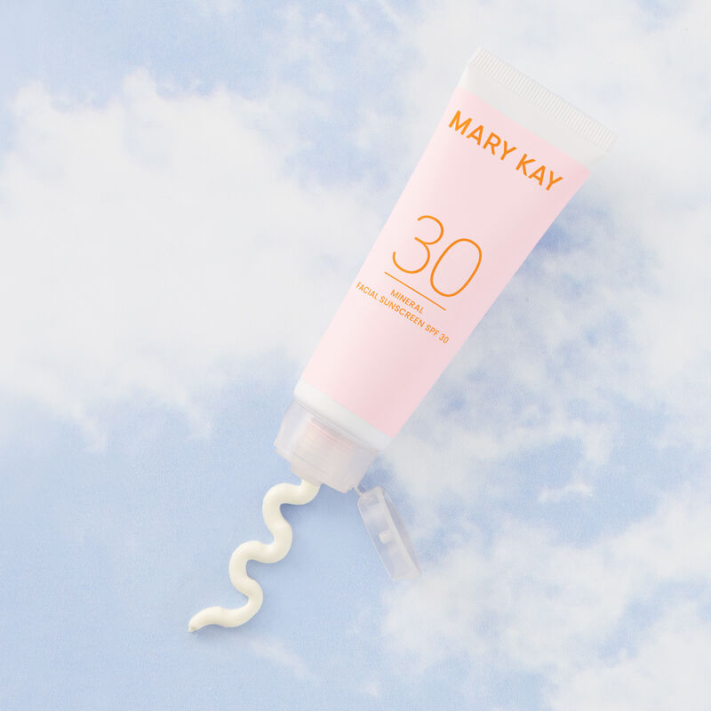 Tube of Mineral Facial Sunscreen SPF 30 squeezing out product against a blue sky with clouds
