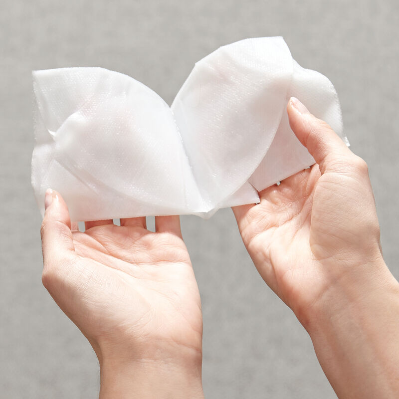 Hands unfolding TimeWise Repair Lifting Bio-Cellulose Mask from Mary Kay.