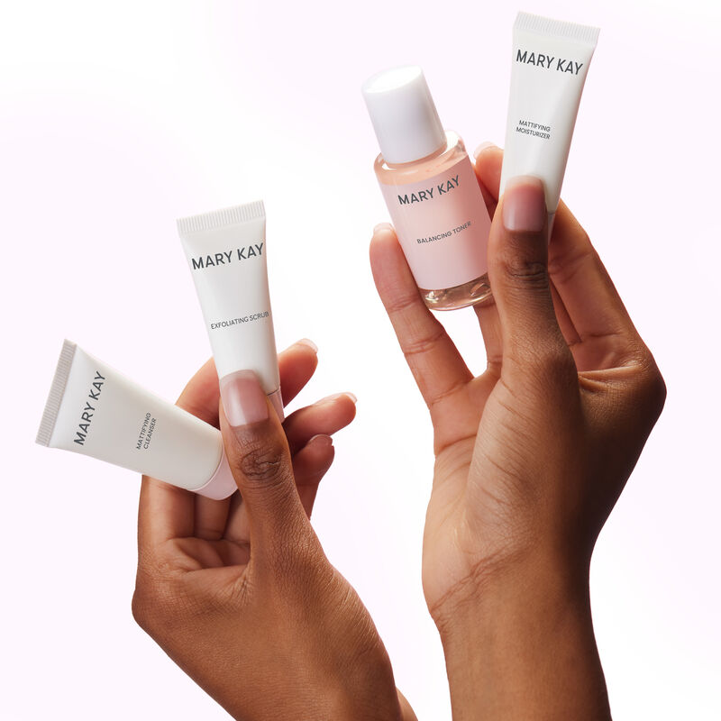 Deep-skinned hands holding miniature bottles of the Mary Kay Mattifying Go Set