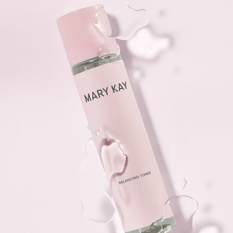 Bottle of Mary Kay Balancing Toner beneath product drops against light pink background
