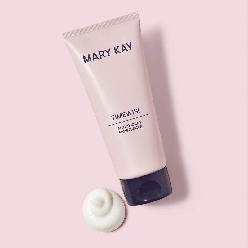 Tube of TimeWise Antioxidant Moisturizer next to product rub against pink background