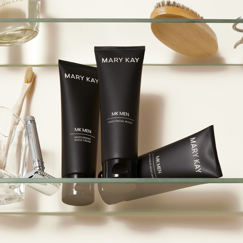 MKMen Moisturizing Shave Cream, Daily Facial Wash and Ultimate Moisturizer on a shelf next to a razor, men&rsquo;s brush and other toiletries.