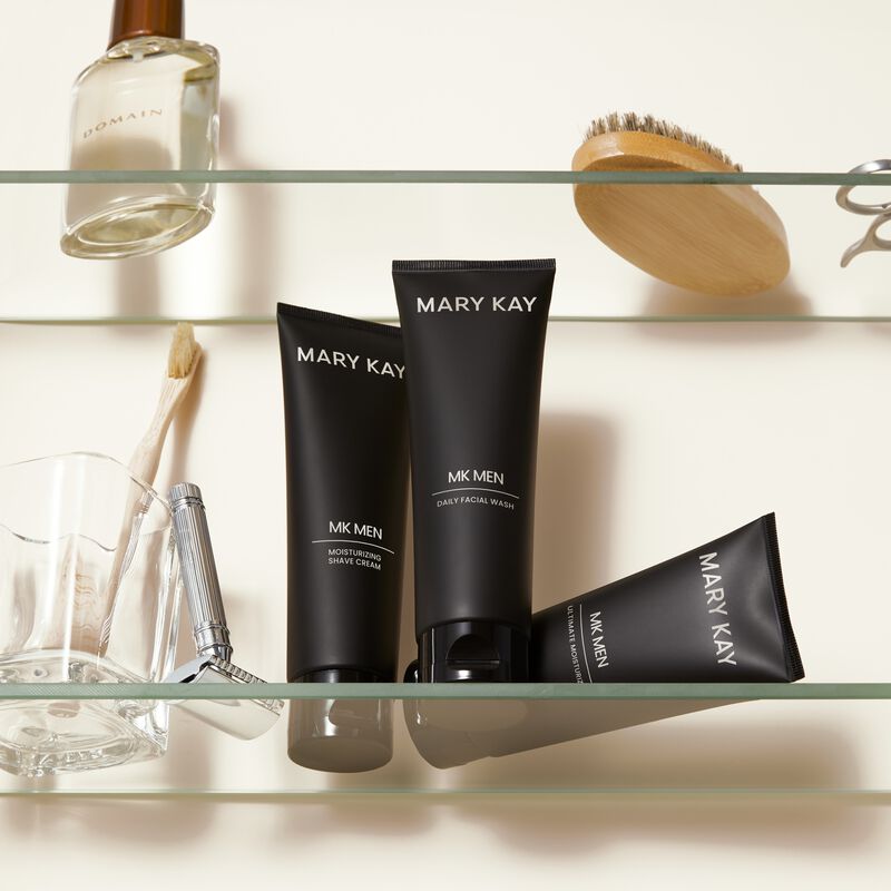 MKMen Moisturizing Shave Cream, Daily Facial Wash and Ultimate Moisturizer on a shelf next to a razor, men&rsquo;s brush and other toiletries.