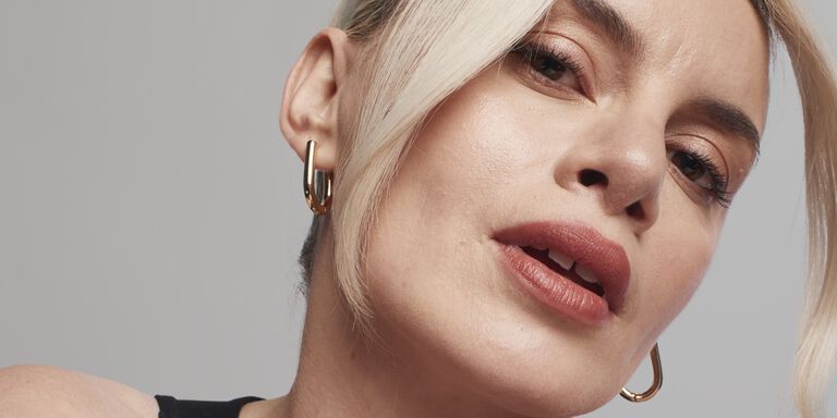 Blonde-haired model looking confidently at the camera while wearing Luminous foundation.