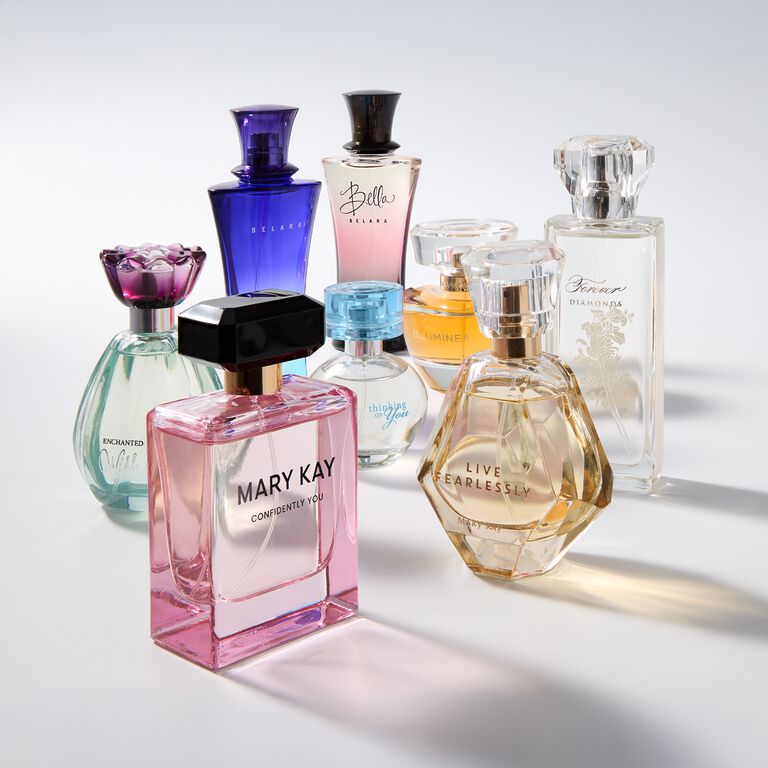 Botellas de fragancias Mary Kay en varias formas y colores, organizadas en una composici&oacute;n elegante.